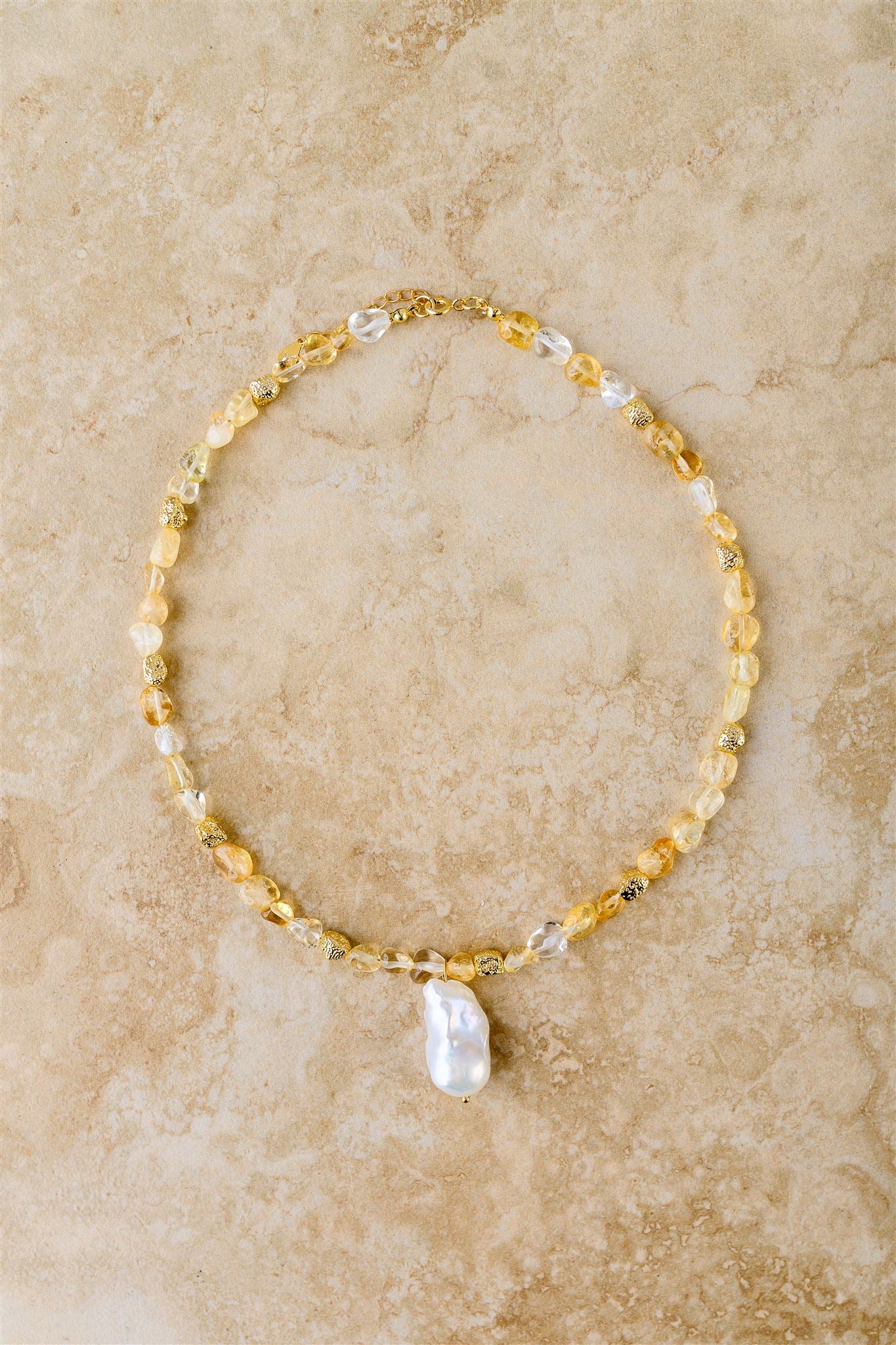 Necklace with yellow and white beads on a beige marble surface