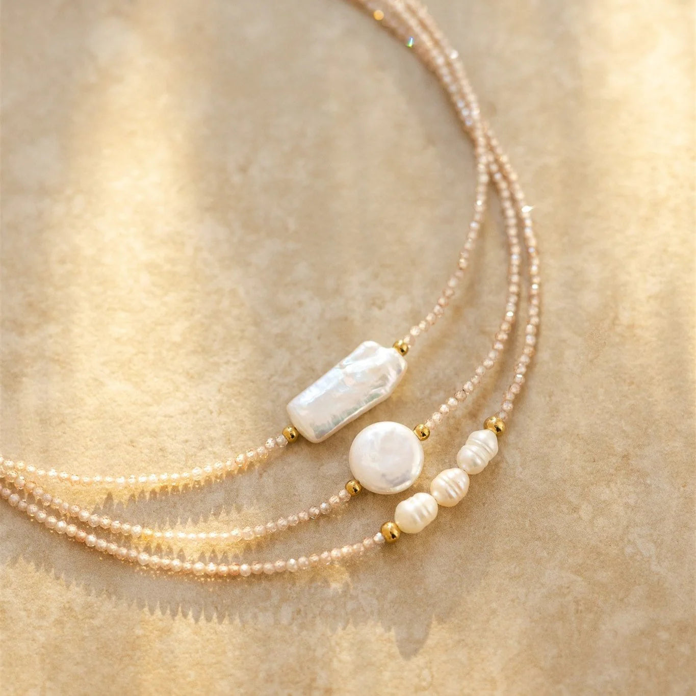 Three-layered pearl necklace with gold accents on a beige background