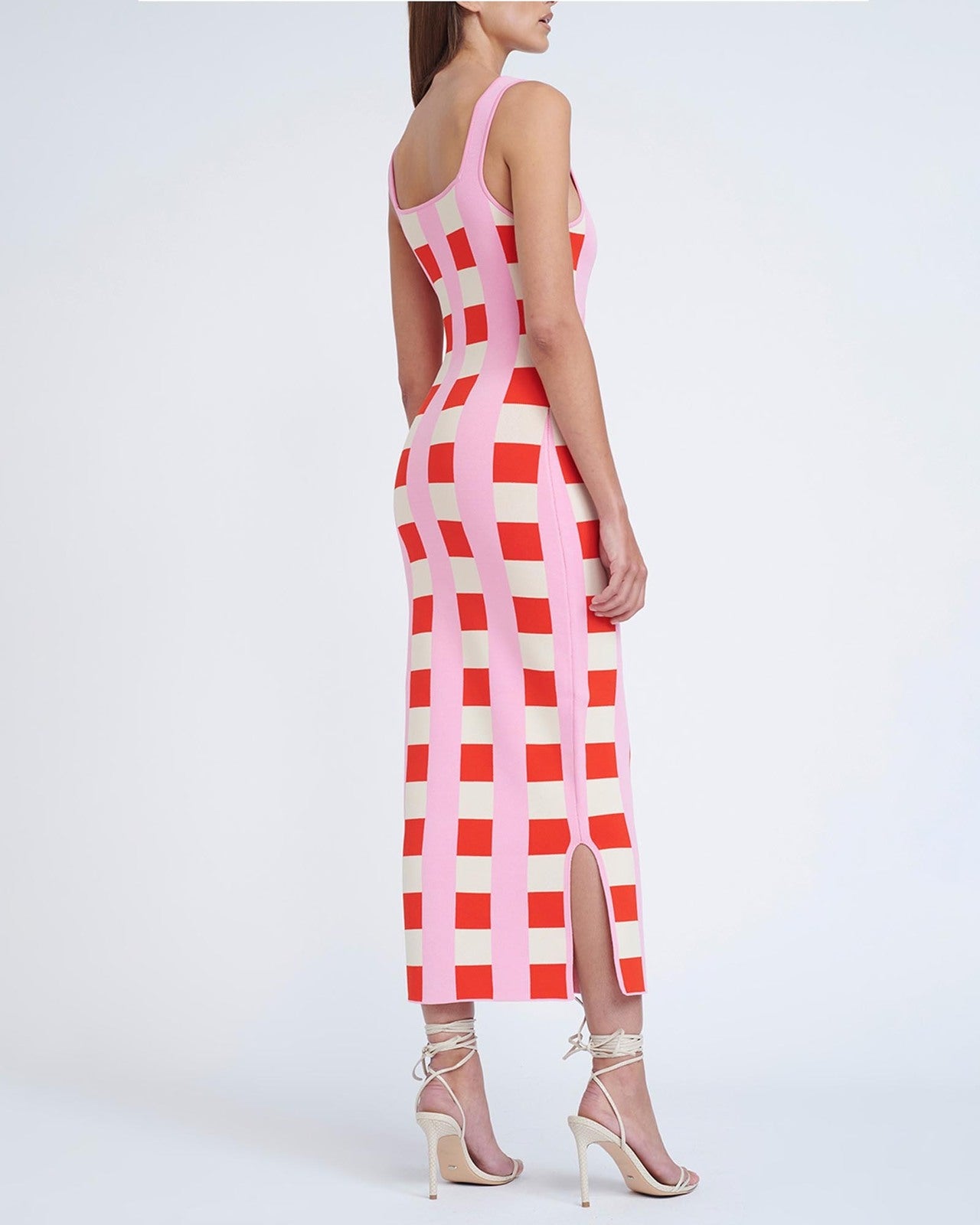 picture of a women standing sideways wearing a pink and red checkered dress