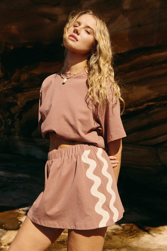 Woman wearing a matching top and shorts with wavy pattern against a dark background
