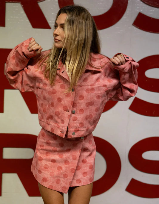 Person wearing a pink polka dot outfit in front of a red and white background